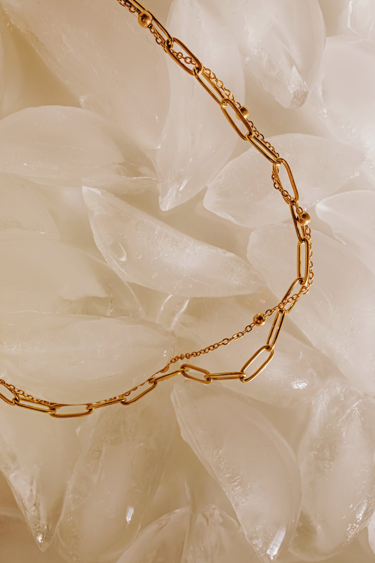 Golden chain necklace lying on the ice. Waterproof jewelry concept.